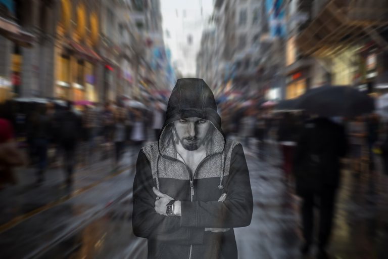 smutny mężczyzna w bluzie z kapturem na tle rozmytego miasta